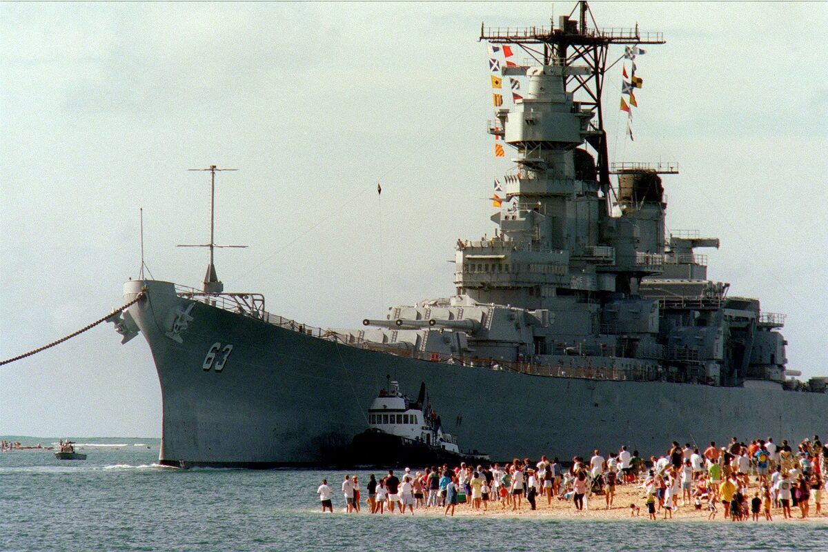 People gather on the beach to see the battleship USS Missouri (BB 63) enter the channel into Pearl Harbor, Hawaii, on June 22, 1998. Secretary of the Navy John H. Dalton signed the Donation Agreement on May 4th, allowing Missouri to be used as a museum near the Arizona Memorial. The ship was towed from Bremerton, Wash. DoD photo by Petty Officer 1st Class David Weideman, U.S. Navy.