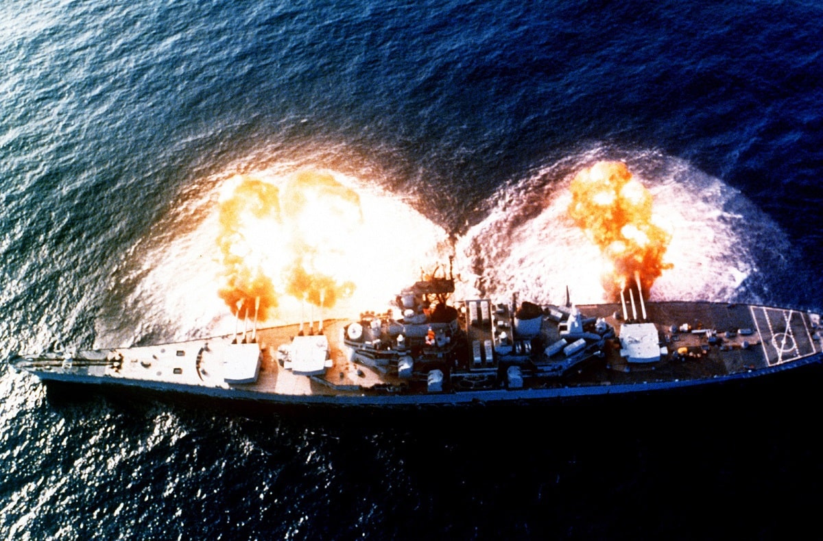 An overhead view of the battleship USS NEW JERSEY (BB-62) firing a full broadside to starboard during a main battery firing exercise. Image Credit: Creative Commons.