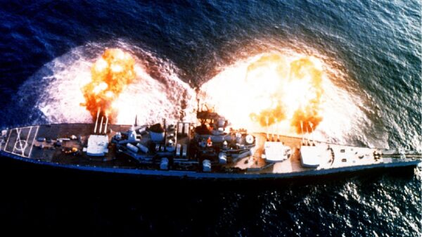 An overhead view of the battleship USS NEW JERSEY (BB-62) firing a full broadside to starboard during a main battery firing exercise. Image Credit: Creative Commons.