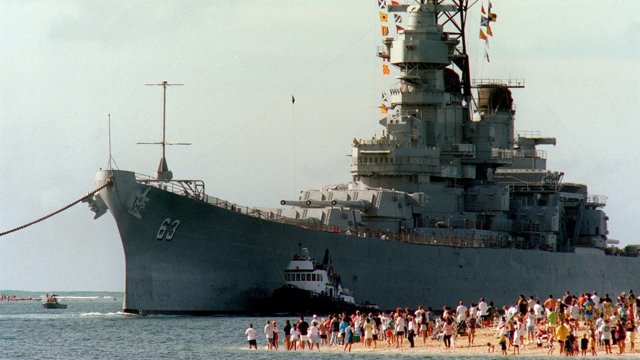 People gather on the beach to see the battleship USS Missouri (BB 63) enter the channel into Pearl Harbor, Hawaii, on June 22, 1998. Secretary of the Navy John H. Dalton signed the Donation Agreement on May 4th, allowing Missouri to be used as a museum near the Arizona Memorial. The ship was towed from Bremerton, Wash. DoD photo by Petty Officer 1st Class David Weideman, U.S. Navy.