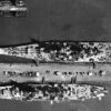 Aerial view of warships at the base piers of Norfolk Naval Base, Virginia (USA), circa August 1944. Among them are: the battleship USS Missouri (BB-63), the largest ship; the battlecruiser USS Alaska (CB-1), on the other side of the pier; the escort carrier USS Croatan (CVE-25), and two destroyers, a Fletcher-class destroyer at the pier and a Clemson/Wilkes-class-destroyer moored outboard. Image Credit: Creative Commons.