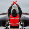 A U.S. Air Force B-1B Lancer crew chief marshals a B-1 after returning from a CONUS-to-CONUS mission in support of Operation Epic Fury, March 4, 2026. The B-1B is a long-range, multi-role bomber that carries the largest payload of precision guided and unguided munitions in the Air Force inventory. (U.S. Air Force photo)