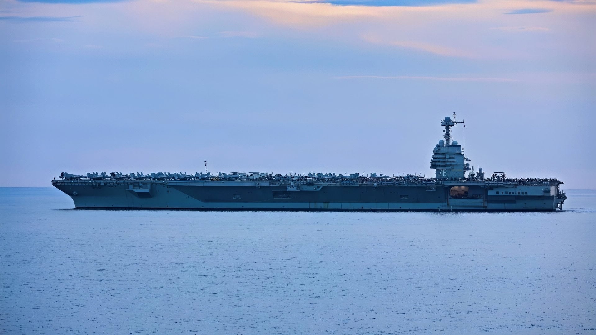 (July 4, 2023) The crew of Ford Class Aircraft Carrier USS Gerald R. Ford (CVN 78) stand on the flight deck to watch a Fourth of July gun shoot from Arleigh Burke-class guided-missile destroyer USS Ramage (DDG 61) (not pictured), July 4, 2023. Ramage is part of the Gerald R. Ford Carrier Strike Group and is on a scheduled deployment in the U.S. Naval Forces Europe area of operations, employed by the U.S. Sixth Fleet to defend U.S., allied, and partner interests. (U.S. Navy photo by Mass Communication Specialist 3rd Class Adriones Johnson)
