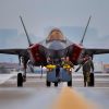 U.S Air Force Senior Airman Kyle Lemanski, left, and Senior Airman Paul Sullivan, crew chiefs assigned to the 421st Fighter Generation Squadron, Hill Air Force Base (AFB), Utah, tow an F-35 Lightning II down the flight line while another F-35 Lightning II taxis during Red Flag-Nellis 24-1 at Nellis AFB, Jan. 22, 2024. This Red Flag will have approximately 30 units and close to 2,000 participants from U.S. and Allied forces. (U.S. Air Force photo by Senior Airman Zachary Rufus)